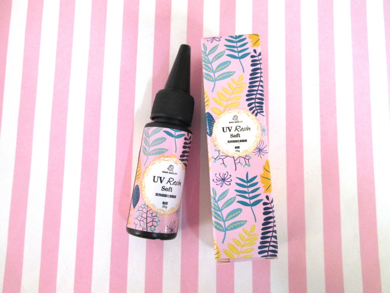May include: A bottle of UV Resin Soft, a clear resin that cures under UV light. The bottle is black with a floral design and the text "UV Resin Soft" on the label. The bottle is next to a box with the same design.