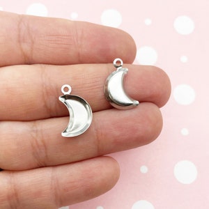 Peut inclure: Deux breloques en métal en forme de croissant de lune argentées avec une boucle en haut pour les attacher à des bijoux ou d'autres objets artisanaux.