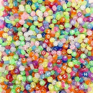 May include: A close-up of a large pile of colourful alphabet beads. The beads are translucent and have white letters on them. The beads are a mix of colours, including pink, blue, green, yellow, orange, and purple.