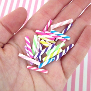 May include: A collection of colourful striped straws in pink, blue, green, yellow, and purple. The straws are made of plastic and are perfect for adding a touch of fun to any party or event.
