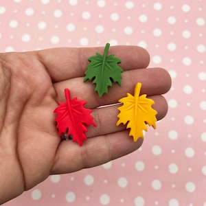 May include: Three felt leaf shapes in red, green, and yellow. The leaves are all the same size and shape, and they are arranged in a row.