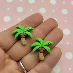 Könnte beinhalten: Zwei grüne Palmen-Anhänger mit braunen Stämmen und Kokosnüssen. Die Anhänger sind aus Polymer Clay gefertigt und perfekt, um deinen Bastelarbeiten einen tropischen Touch zu verleihen.