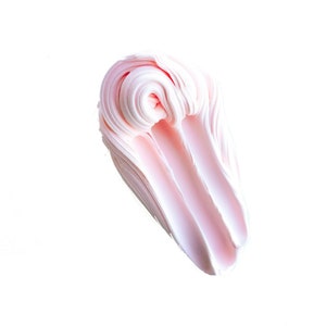 May include: A swirl of light pink, creamy substance against a white background. The texture appears smooth and soft, with visible layers and a slight sheen. The shape is elongated and rounded, resembling a stylized brushstroke.