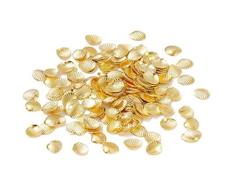 May include: A pile of gold-colored metal seashells, scattered on a white background.