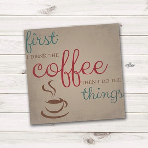 Puede incluir: Un letrero beige con texto marrón que dice "first I drink the coffee then I do the things". El texto "coffee" está en rojo y el texto "things" está en turquesa. Una taza de café marrón con vapor que sale de ella se representa en el centro del letrero.