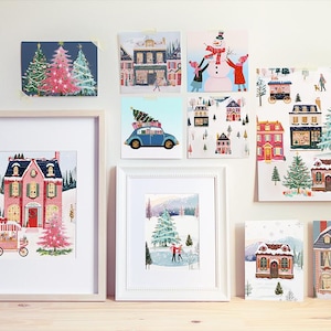 May include: A collection of eight framed illustrations featuring winter scenes with houses, trees, and snow. The illustrations are in a variety of styles, including cartoon, realistic, and abstract.