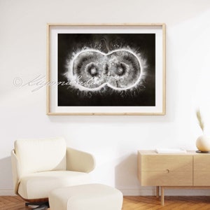 May include: A black and white abstract watercolor painting of an infinity symbol with a white center and a black background. The painting is framed in a light wood frame.