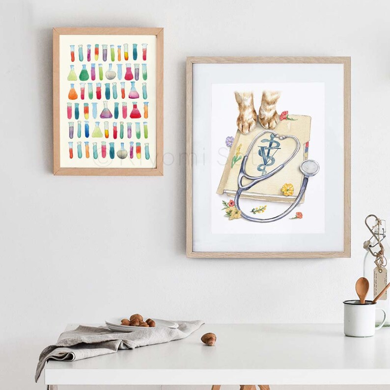 May include: A watercolor painting of a book with a stethoscope on top of it. The book has a green veterinary symbol on the cover. The stethoscope is blue and has a silver earpiece. The book is surrounded by flowers. The painting is framed in a light wood frame.