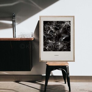 May include: A framed art print featuring a black and white abstract design resembling neurons. The artwork is set against a neutral background and is labeled "NEURON" at the bottom. The frame is light-colored wood, and the print is displayed on a small stool.