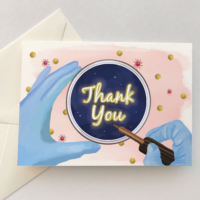 May include: A pink and blue thank you card with a petri dish and a dropper. The petri dish has a blue background with gold stars and the words "Thank You" in gold lettering. The card is decorated with gold dots and red virus illustrations.