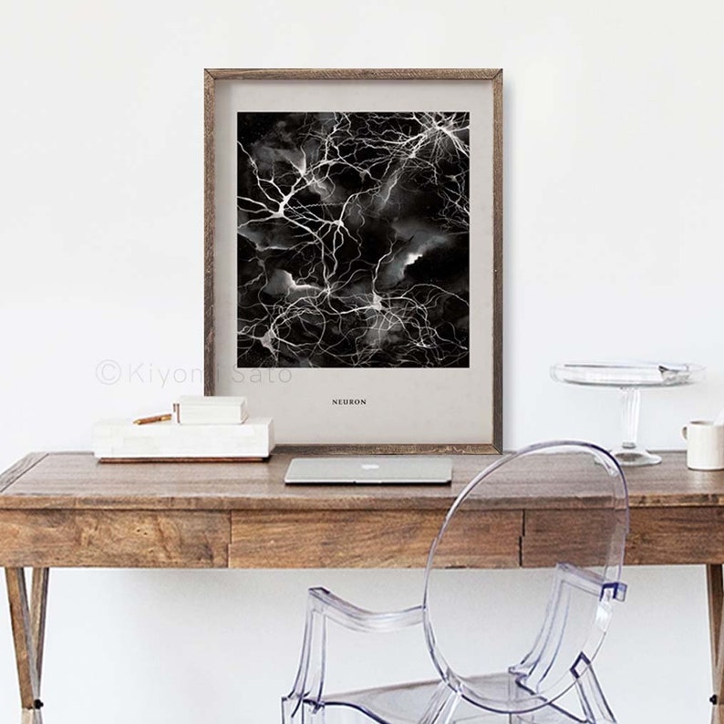 May include: A framed art print featuring a black and white abstract design resembling neural networks. The print is labeled "NEURON" and is displayed on a wooden desk with a laptop, a white box, and a clear plastic chair.