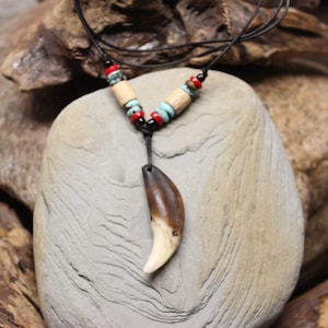 May include: A brown and white animal tooth pendant on a black leather cord with turquoise and red beads.