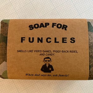May include: A bar of soap wrapped in brown paper with the text "SOAP FOR FUNCLES." The label also states the soap "SMELLS LIKE VIDEO GAMES, PIGGY-BACK RIDES, AND CANDY." The soap has a camouflage pattern.