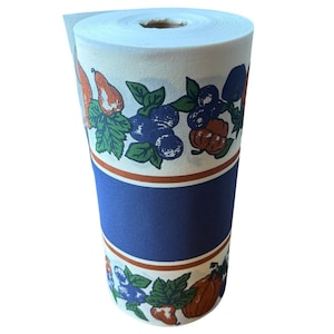 May include: A roll of white and blue patterned paper with a repeating design of blue berries, green leaves, and orange pumpkins. The paper is rolled up and ready to be unrolled.