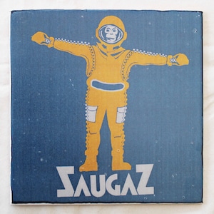 May include: A yellow astronaut with a monkey face in a blue space suit with the word "SAUGAZ" printed in white letters on a blue background.