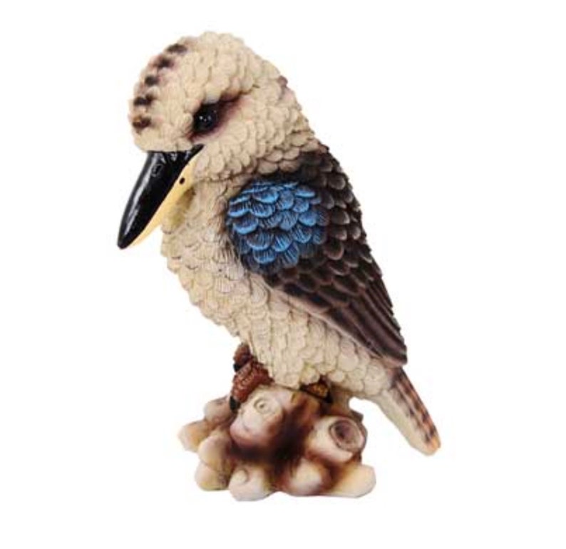 May include: A small, detailed figurine of a kookaburra bird perched on a tree branch. The bird is brown and white with blue feathers on its wings. The figurine is made of resin and is a great addition to any home decor.
