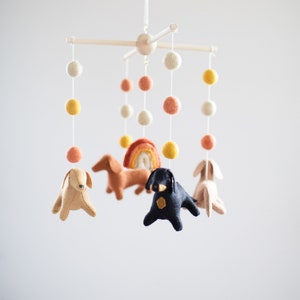 May include: A white wooden baby mobile with felt dachshund dogs, a rainbow, and colorful pom poms.