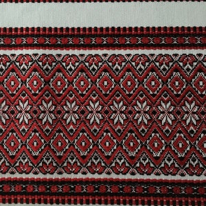 May include: Red and black embroidered fabric with a geometric pattern. The fabric has a white background and is woven with a traditional design.