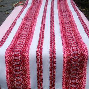 Peut inclure: Tissu blanc avec des rayures brodées rouges et roses. Le tissu a un motif traditionnel.