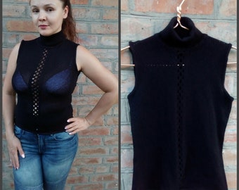 May include: Black sleeveless turtleneck sweater with a delicate openwork design. The sweater is made of a soft, knit fabric.