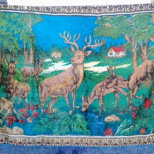 May include: A vintage tapestry featuring a blue background with a forest scene.  The tapestry depicts a family of deer, including a large stag with antlers, standing in a lush green forest with a small house in the background.