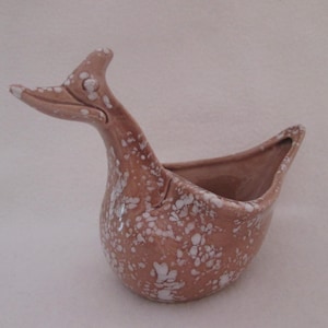 May include: A ceramic planter shaped like a bird with a speckled brown and white glaze.
