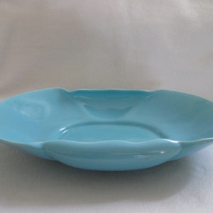 May include: A light blue ceramic serving bowl with a scalloped edge. The bowl is oval shaped and has a smooth, glossy finish.