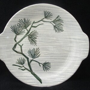 May include: A white ceramic serving platter with a green pine tree design. The platter has two handles on the sides.