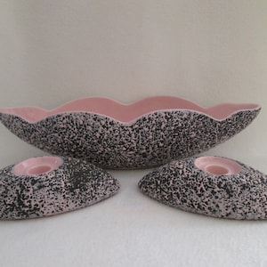May include: A set of three pink and black ceramic bowls. The large bowl is oval shaped with a wavy edge. The two smaller bowls are round and have a flat base. The bowls have a speckled pattern.