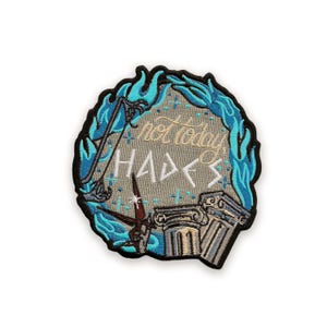 May include: Embroidered patch with a light gray background, featuring the text "not today HADES" in gold and white. A blue flame design surrounds the text, with a bow and arrow and Greek columns.