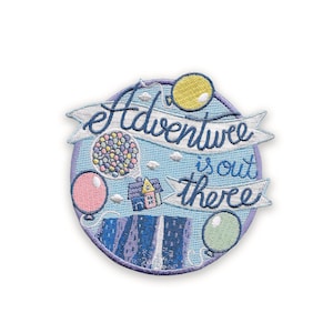 May include: Embroidered patch with a light blue background and a purple border. The patch features the words "Adventure is out there" in white script on a banner. It also includes colorful balloons, a house, and a cluster of colorful dots.