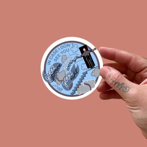 May include: A circular sticker with a light blue and white design. The sticker features the text "In case I don't see you" and the phrases "good afternoon, good evening, good night." A cartoon figure is depicted on a staircase.