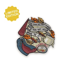 Puede incluir: Un parche bordado colorido con el texto "YOU CAN DO ANYTHING IF YOU SET YOUR MIND TO IT". El parche presenta un diseño de dibujos animados con un sombrero rojo, un abrigo azul y una roca con la lengua fuera. Una pegatina amarilla de "EDICIÓN LIMITADA" está en la parte superior izquierda.