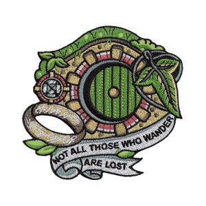 Puede incluir: Parche bordado con una puerta verde de hobbit, un anillo dorado y el texto "NOT ALL THOSE WHO WANDER ARE LOST" en una pancarta. El parche tiene un diseño detallado con hojas verdes y un emblema circular.