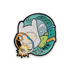 Può includere: Toppa ricamata con un personaggio dei cartoni animati con una testa bianca e un design circolare. La toppa include una combinazione di colori blu, verde, giallo e arancione. Il design include la parola "MO" e un fulmine.