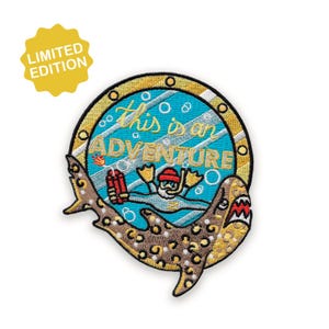 Puede incluir: Parche bordado con un diseño de tiburón. El parche presenta un buceador con el texto "This is an Adventure" en un marco circular. El tiburón tiene un patrón de estampado de leopardo. Una etiqueta amarilla de "Edición Limitada" está en la esquina superior izquierda.