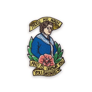 Op de afbeelding: Geborduurde patch met een vrouw in een blauwe jas en een bril. De patch heeft de tekst "Touch me again" en "And I'll drown you you bastard" in een banner- en scrollontwerp, omgeven door bladeren en een roos.