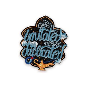 May include: Embroidered patch with the phrase "Often Imitated Never Duplicated" in light blue script. The patch features a black background with a gold border, a genie lamp, and stylized clouds.