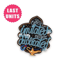 May include: Embroidered patch with the phrase "Often Imitated, Never Duplicated" in blue script. The patch features a black background with a gold outline, a genie lamp, and a pink "Last Units" sticker.
