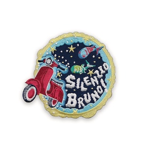 Può includere: Toppa ricamata con uno scooter rosso, pesci e stelle su sfondo blu scuro. La toppa riporta la scritta "SILENZIO BRUNO!" in bianco, con un bordo smerlato giallo. Un design divertente e stravagante.