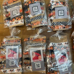May include: Several packages of hair ties and sleeve ties are displayed. The hair ties feature basketball and polka dot patterns. The sleeve ties are packaged with a tag that reads "Sleeve Ties KTeow on Etsy". The packages are sealed in clear plastic.
