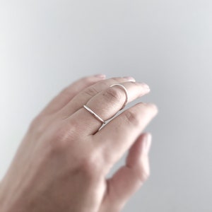 May include: Two silver rings on a finger. The rings are simple and minimalist in design.