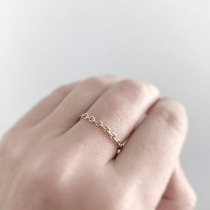 May include: A gold chain ring on a finger.