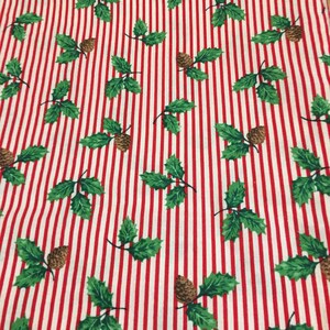 May include: Red and white striped fabric with a repeating pattern of green holly leaves and brown pine cones.
