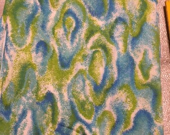 May include: A white fabric with a blue and green abstract pattern. The pattern resembles swirling clouds or water.