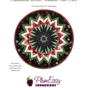 May include: A round, folded star table topper with a diameter of 17 inches. The design features a starburst pattern in red, green, white, and black. The text "Point of View Kaleidoscope" and "FOLDED STAR TABLE TOPPER" are visible.