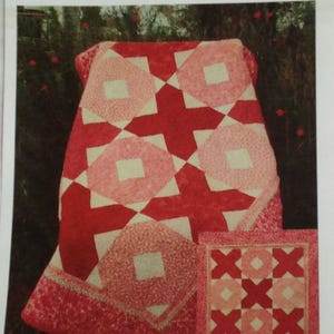 May include: A red and pink quilt pattern with the text "Kwik Hugs and Kisses". The quilt features a repeating pattern of circles and crosses. A smaller quilt with an XOX pattern is also shown.