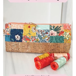 May include: A patchwork pencil pouch with a cork bottom. The pouch features a variety of floral fabric squares and a zipper closure. The text "Cork Bottom Pencil Pouch" is displayed at the top. The finished size is 5" x 12" x 2".
