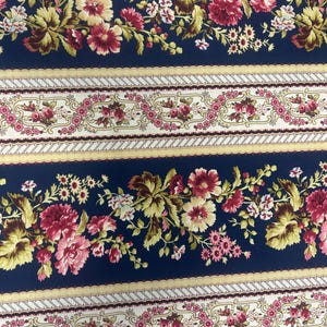May include: Navy blue fabric with a repeating pattern of pink and yellow flowers and a white and gold ornate border.