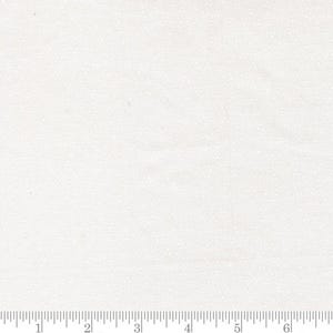 May include: A white fabric featuring a subtle, repeating pattern of tiny, light-colored dots. A ruler is positioned along the bottom edge, showing a scale in inches that extends from zero to seven inches across the width of the textile material.